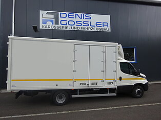 Weißer LKW vor einer Werkstatt mit Schild.