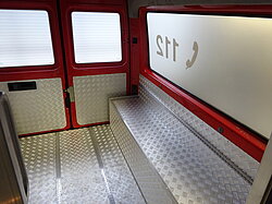 Innenansicht eines roten Einsatzfahrzeugs mit Metallboden und 112 auf dem Fenster.