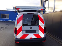 Rückansicht eines Vans mit roten und weißen Warnstreifen.