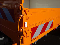 Nahaufnahme des Rückens eines orangefarbenen LKWs mit roten Streifen.