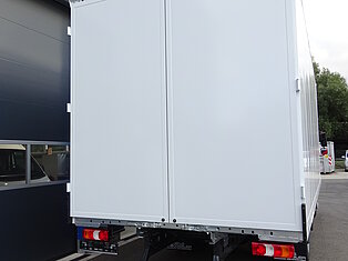 Rückansicht eines weißen LKWs, der in der Nähe eines Gebäudes parkt.