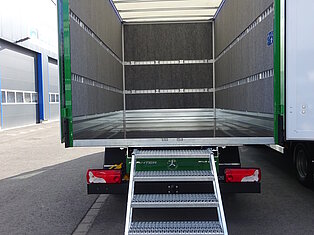 Offener LKW mit Metalltreppe ins Innere.