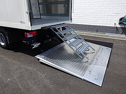 LKW mit offener Rampe und Metalltreppe.