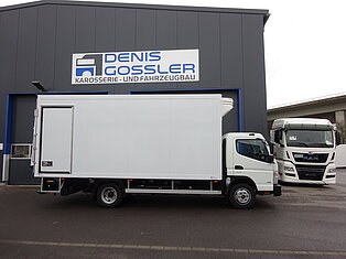 Weißer LKW vor einer Fahrzeugwerkstatt geparkt.
