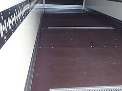 Innenansicht eines leeren Laderaums mit Schienen an den Wänden.