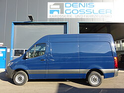 Blauer Lieferwagen vor einer Werkstatt mit Schild