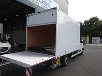 Ein weißer LKW mit offenem Laderaum und Rampe.