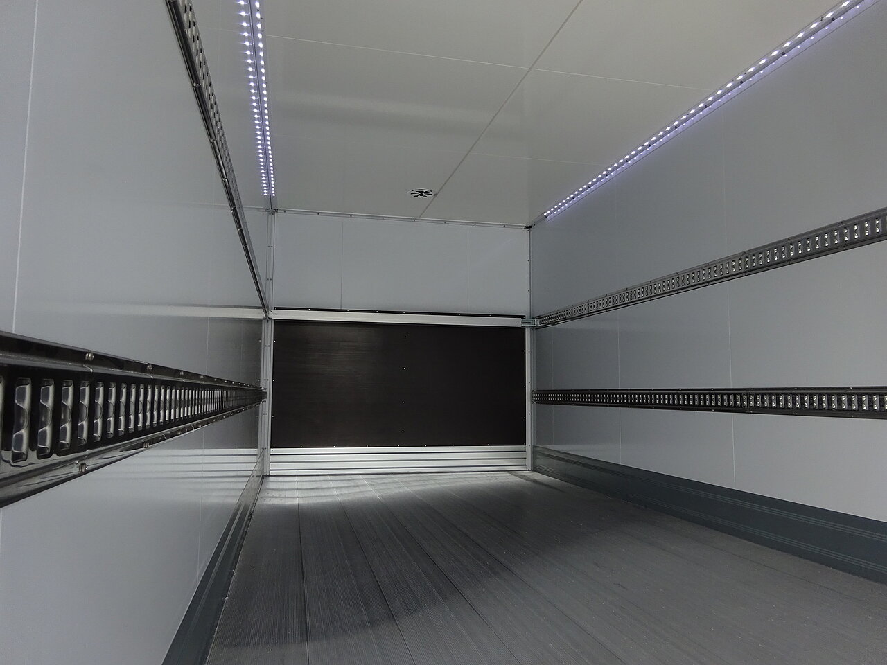 Innenansicht eines leeren LKW-Laderaums mit Metallschienen.