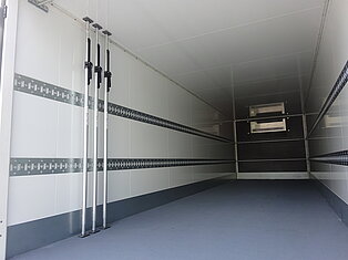 Innenansicht eines leeren LKW-Anhängers mit Metallstangen.