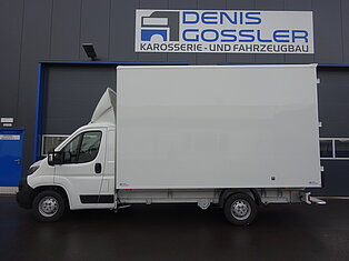 Weißer Lieferwagen vor einem Gebäude mit Denis Gossler Schild