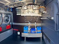 Innenraum eines Vans mit Waschmaschinen und Wassertanks.