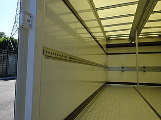 Innenansicht eines leeren LKWs mit Metallschienen.