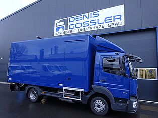 Blauer LKW vor einem Gebäude mit Werkstattschild