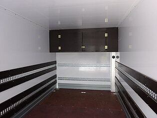 Innenraum eines leeren LKWs mit Holzpaneelen und Metallschienen.