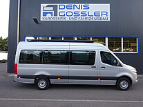 Silberner Transporter vor einer Werkstatt mit Schild