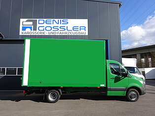 Grüner LKW vor einem Werkstattgebäude geparkt.