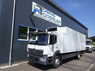 Weißer LKW vor einem Gebäude mit Firmenlogo