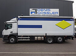 Weißer LKW vor einem Gebäude mit Firmenlogo