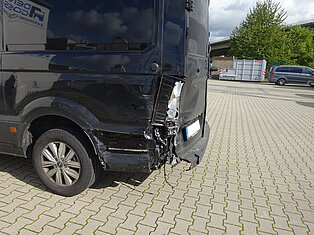 Heck eines schwarzen Vans mit erheblichen Schäden.