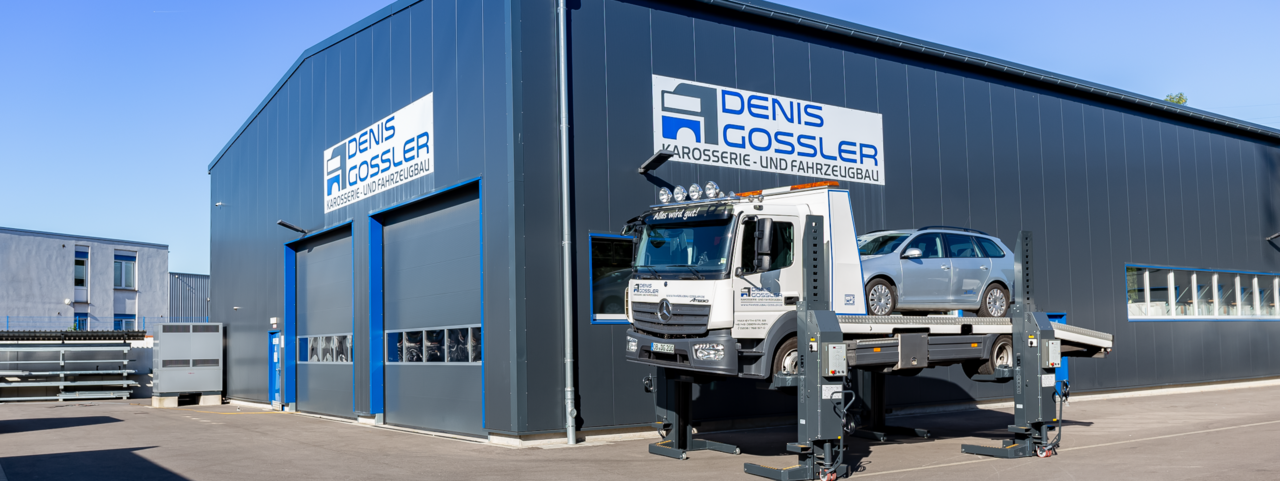 Gebäude von Denis Gossler Karosseriewerkstatt mit Abschleppwagen und Auto
