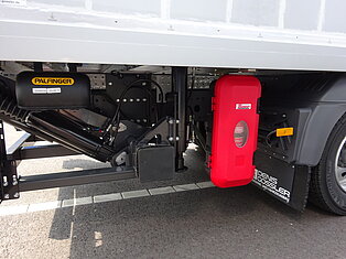 Nahaufnahme des LKW-Unterbaus mit Hydraulikteilen.