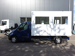Blauer LKW mit weißer Bürokabine im Freien geparkt.
