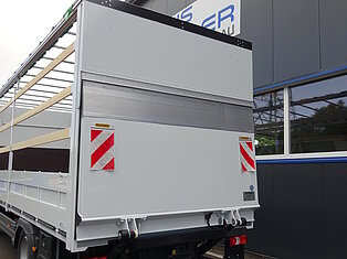 Rückansicht eines LKW-Anhängers neben einem Gebäude.