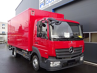 Roter LKW vor einer Fahrzeugwerkstatt geparkt.