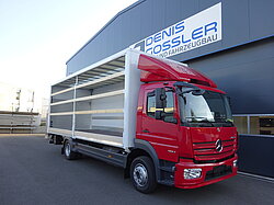 Roter LKW vor einem Fabrikgebäude geparkt.