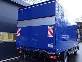 Blauer LKW vor einem Gebäude mit Werkstattschild