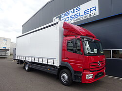 Roter LKW vor einem Industriegebäude geparkt.