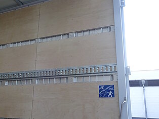 Innenansicht eines Lkw mit Holzverkleidung und Warnschild.