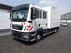 Weißer MAN-Lkw auf Asphalt nahe Gebäude geparkt.