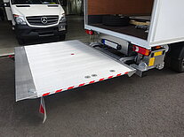 LKW mit offener Hebebühne in einer Garage.