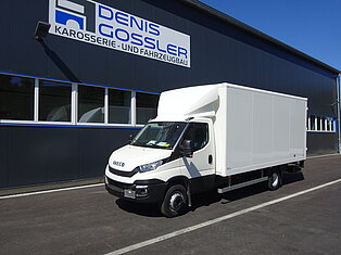 Weißer LKW vor einer Fahrzeugwerkstatt geparkt.