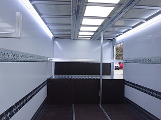 Innenansicht eines leeren LKW-Laderaums mit Metallschienen.
