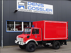 Rotes Feuerwehrauto vor einer Werkstatt geparkt.