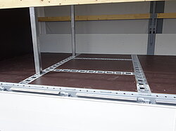 Innenansicht eines LKW-Laderaums mit Metallschienen.