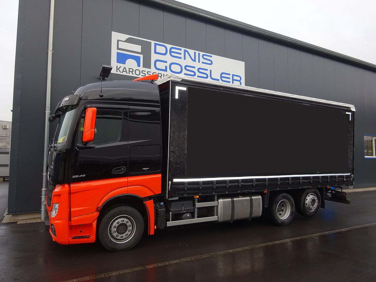 Schwarz-oranger LKW am Servicezentrum geparkt.