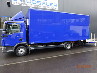 Ein blauer Lieferwagen vor einem Gebäude geparkt.