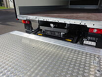 Offener LKW mit ausgefahrener Metallrampe.