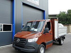 Brauner Lieferwagen vor einem blauen Gebäude mit Schriftzug.