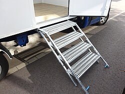 Metalltreppe führt zu einer offenen Fahrzeugtür.