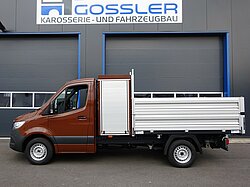 Brauner LKW vor einer Werkstatt mit Beschilderung geparkt.