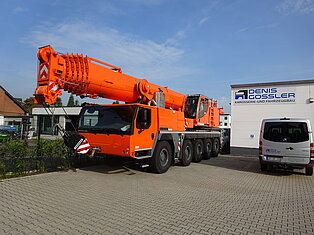 Großer orangefarbener Kran vor einem Gebäude geparkt.