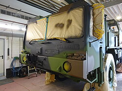 Militärfahrzeug in Werkstatt mit abgeklebten Fenstern.