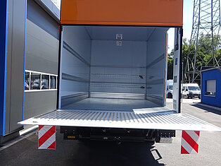 Offener LKW-Laderaum mit orangefarbener Tür.