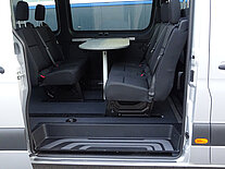 Innenraum eines Vans mit Sitzen und einem Tisch.