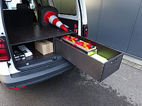 Offener Transporter mit Schublade und Verkehrskegel.