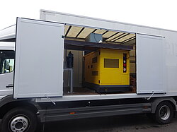 Ein geöffneter LKW mit einem gelben Generator im Inneren.
